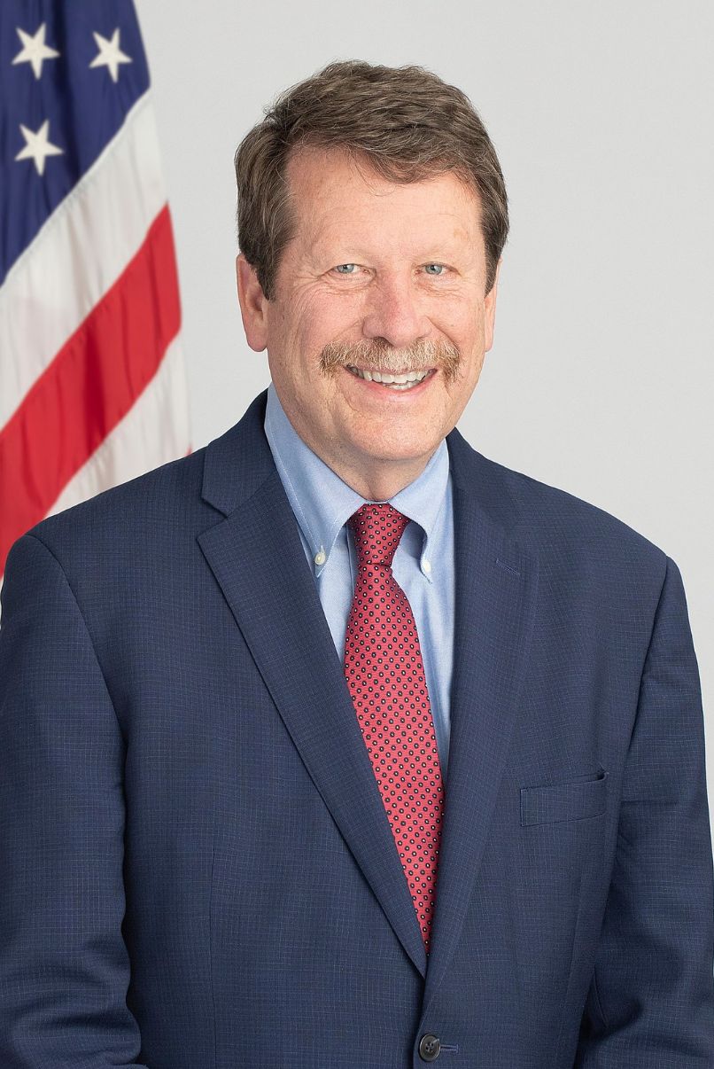 Robert Califf next to a US flag